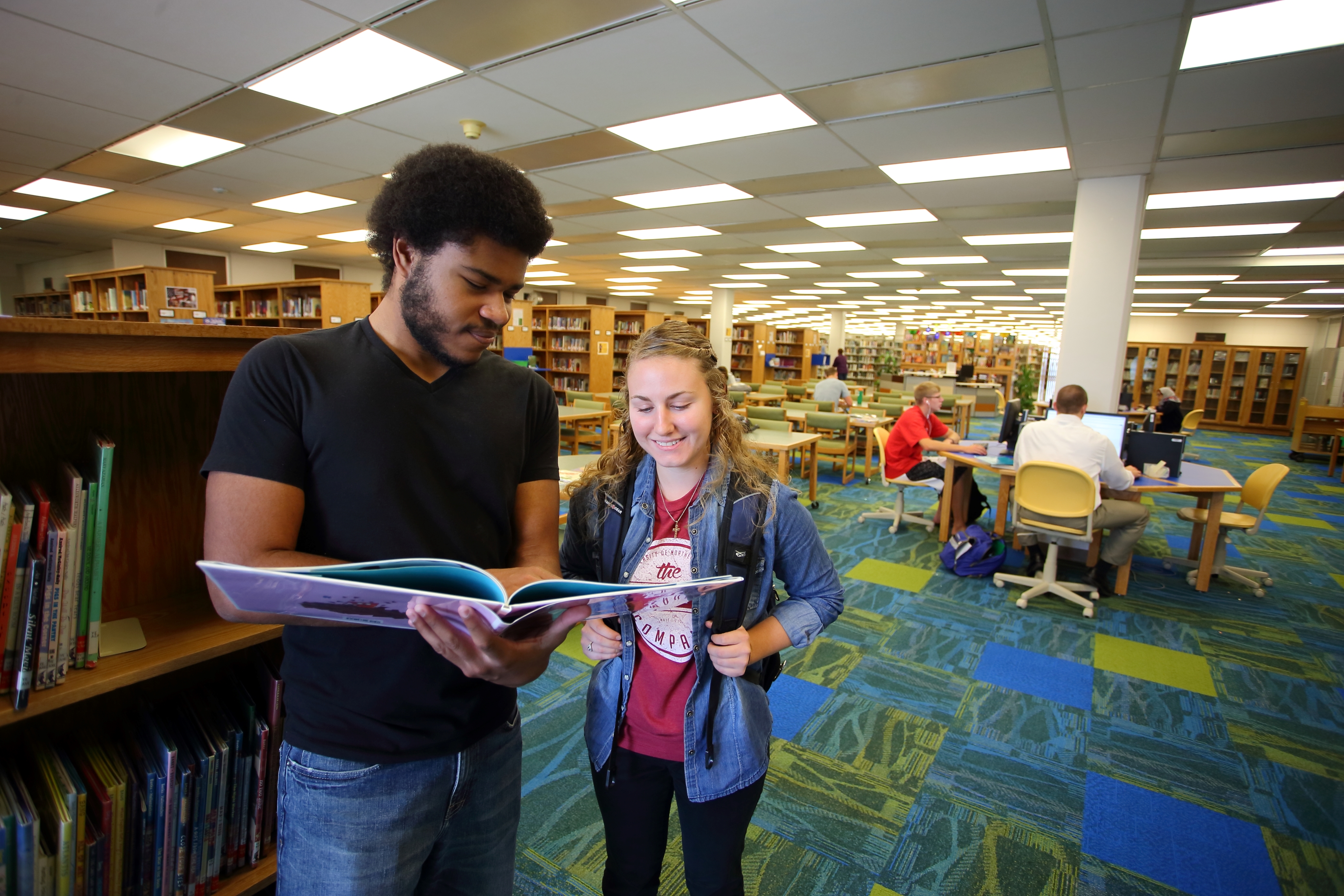 Students looking at a book in the Youth Collection at Rod Library.